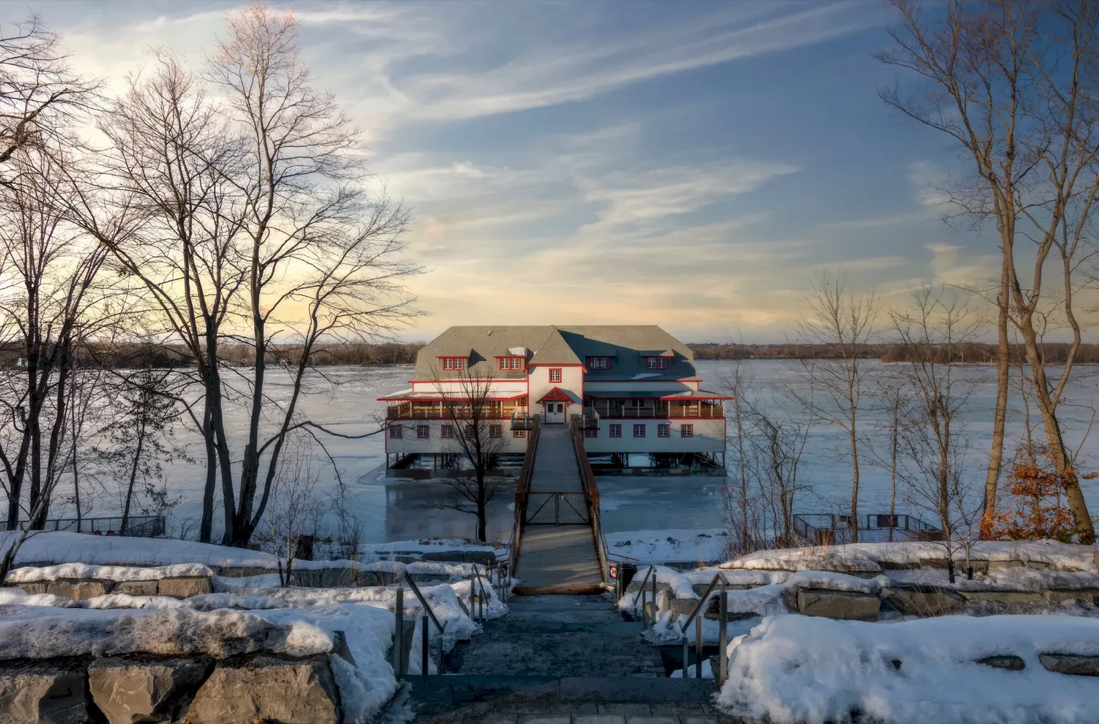 The NCC River House on the Ottawa River at golden hour, with the floating sauna moored alongside