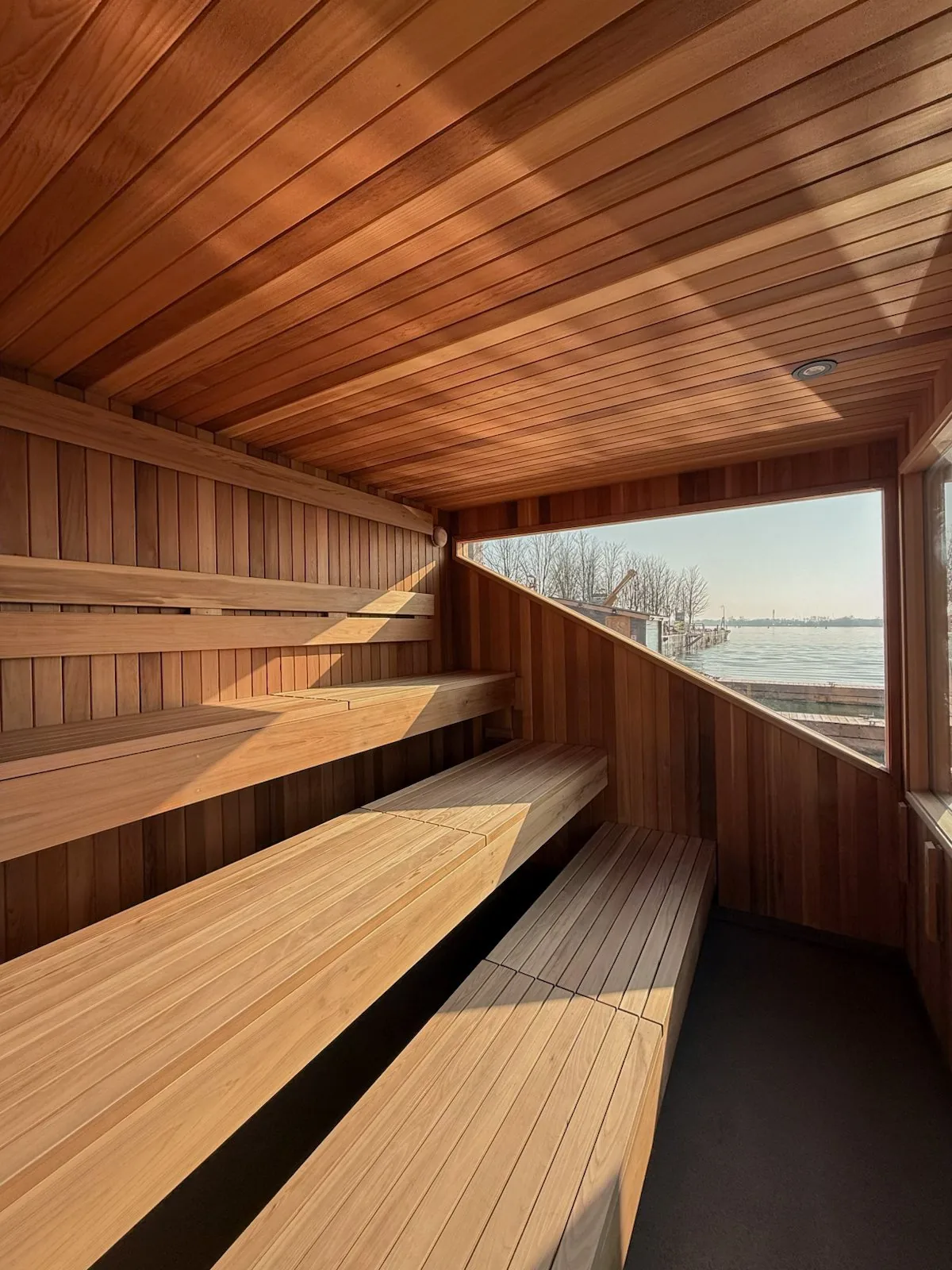 Cedar benches inside the sauna, with the window looking out over the water